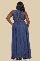 Woman wearing a blue denim dress with cut-out back on a beige background