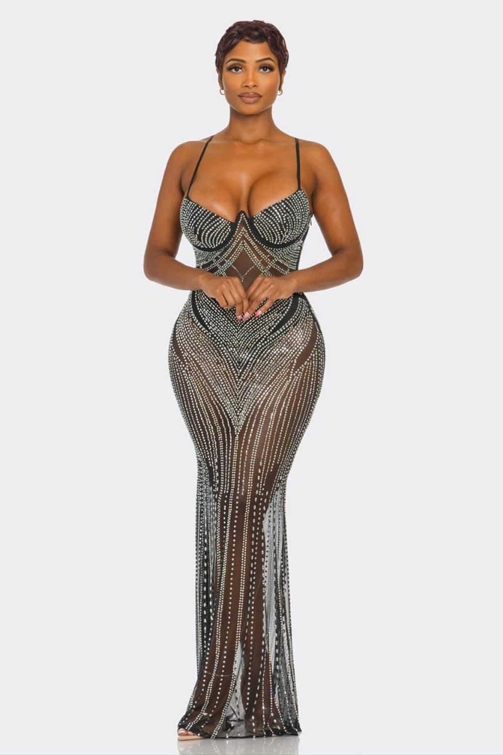 A woman modeling a floor-length, bodycon evening gown covered in silver rhinestones over a sheer black mesh base, set against a solid light gray background.