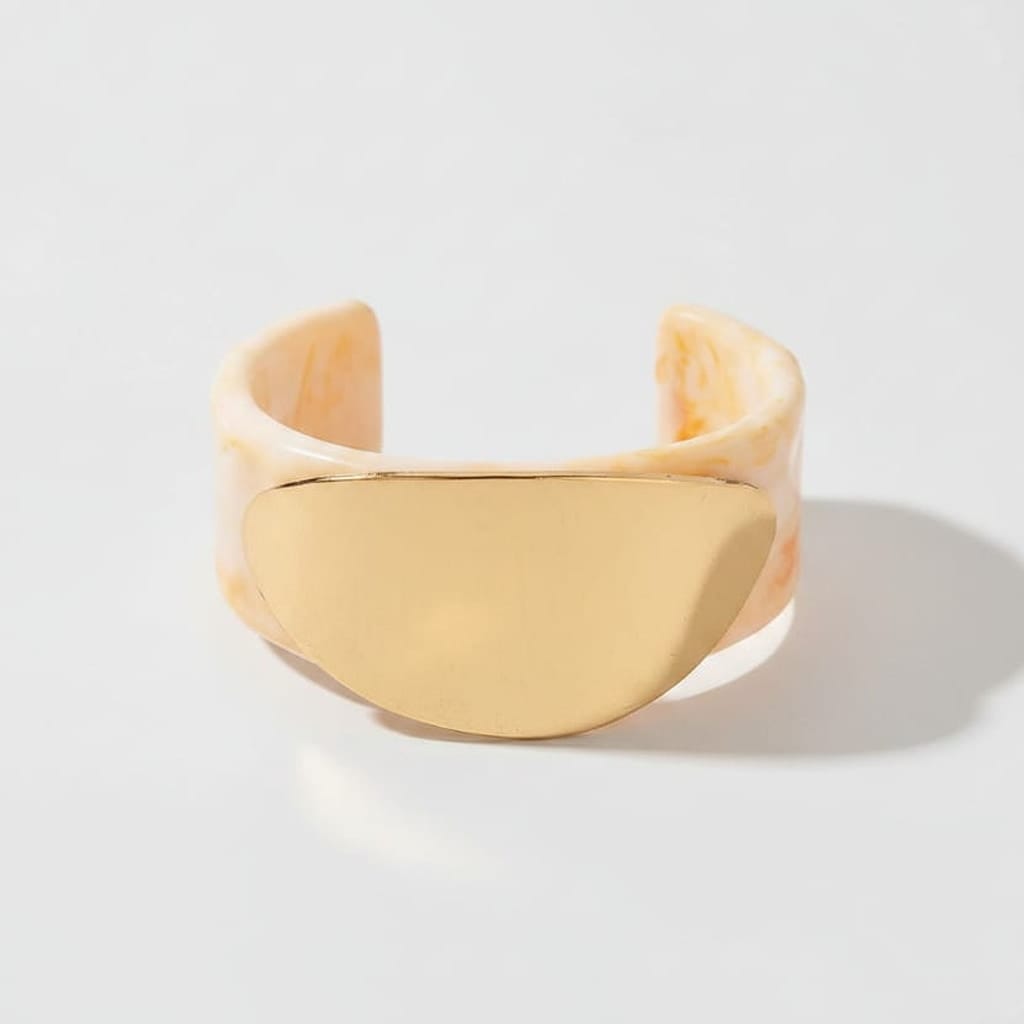 Gold cuff bracelet on a beige background