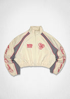 Men's ecru cropped zip track jacket with paneled body and varsity-style patch details - front